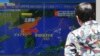 A man stands along a sidewalk to watch a TV showing a news program on North Korea's missile launch, July 12, 2023, in Tokyo.