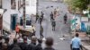 Des gens retirent un débris de la route alors que des soldats comoriens patrouillent à la suite d'une manifestation de l'opposition à Moroni le 17 janvier 2024, suite à l'annonce des élections présidentielles.