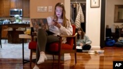 FILE - Kate Bulkeley uses her phone to print textbook pages while Sutton packs art materials ahead of a ski vacation, Feb. 16, 2024, in Westport, Conn.