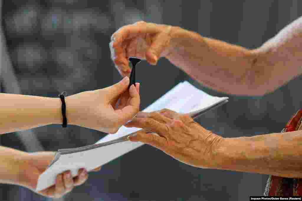 A woman receives a stamp and voting ballots to cast her vote for the European Parliament election and the local elections, in Bucharest, Romania, June 9, 2024.