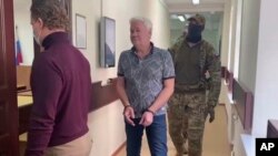 FILE - In this handout photo taken from video released by Lefortovo District Court, Robert Shonov walks to the court room in Moscow, Russia, May 18, 2023.