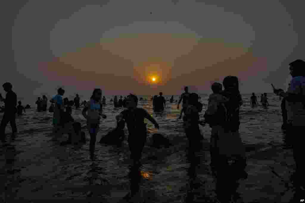 Ljudi se okupljaju na plaži Juhu na obali Arapskog mora dok sunce zalazi u novogodišnjoj noći u Mumbaiju, Indija, 31. decembra 2023.