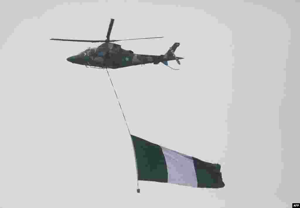 A Nigeria military helicopter carries the Nigeria flag during the inauguration of Nigeria President Bola Ahmed Tinubu at the Eagle Square in Abuja, Nigeria, May 29, 2023.