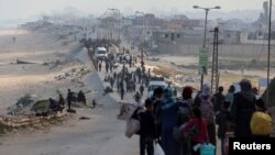 Palestinians, who were displaced by Israel's military offensive on south Gaza, make their way as they attempt to return to their homes in north Gaza through an Israeli checkpoint, as seen from central Gaza Strip April 15, 2024. 
