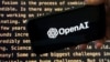 FILE - The OpenAI logo appears on a mobile phone in front of a screen showing part of the company's website in this photo taken in New York on Nov. 21, 2023.