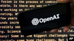 FILE - The OpenAI logo appears on a mobile phone in front of a screen showing part of the company's website in this photo taken in New York on Nov. 21, 2023.