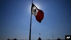 FILE - A Mexican flag waves in front of The National Palace, the office of the president, in Mexico City's main square, the Zocalo, at sunrise, April 24, 2023.