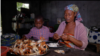 Charlotte Cocodji, avec son fils à ses côtés, nettoyant les crabes dans sa cuisine du Cap Estérias, au nord de Libreville, au Gabon. Août 2022.