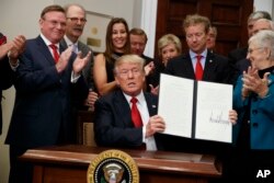 President Donald Trump shows an executive order on health care that he signed in the Roosevelt Room of the White House, Oct. 12, 2017, in Washington.