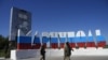 Tentara Rusia berjalan melewati nama kota Mariupol yang dicat ulang dengan warna bendera Rusia di pintu masuk Mariupol, di Donetsk, Ukraina timur, Minggu, 12 Juni 2022. (Foto: AP)