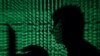 FILE - A man holds a laptop computer as cyber code is projected on him in this illustration made May 13, 2017. The U.N. High Commissioner for Human Rights estimated this summer that the cybercrime industry has victimized 100,000 people in Cambodia.