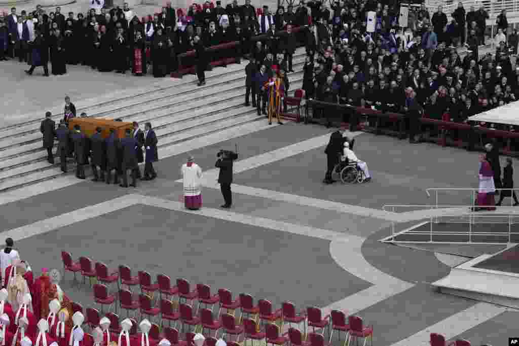 Pope Francis is pushed away on a wheelchair while the coffin of late Pope Emeritus Benedict XVI is carried away after a funeral mass in St. Peter's Square, Jan. 5, 2023.