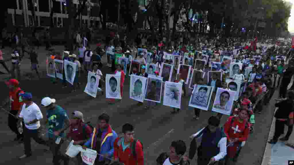 Para kerabat memegang poster bergambar 43 mahasiswa yang hilang,&nbsp;dalam protes di Mexico City&nbsp;(5/11).&nbsp;(AP/Marco Ugarte) 