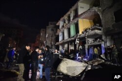 FILE - People gather in the aftermath of a multiple explosive attack in the Sayyida Zeinab area, 10 kilometers south of Damascus, Syria, Feb. 21, 2016. The Islamic State group claimed responsibility for a triple blast in the Shi'ite suburb.