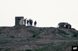 Fighters of People's Protection Units, or YPG, gather at their outpost west of the city of Kobani, northern Syria, Tuesday, Dec. 18, 2018.