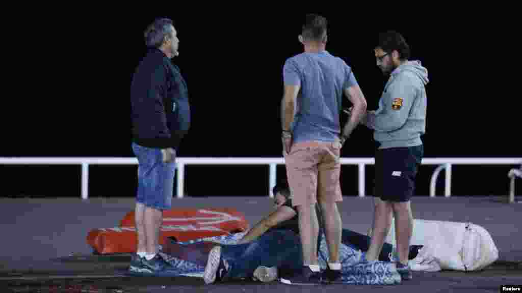 Une personne blessée, assise au sol, est assistée par des passants après l'attaque de Nice, France, 14 juillet 2016.