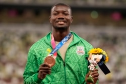 Le médaillé de bronze Hugues Zango, du Burkina Faso, pose lors de la cérémonie de remise des médailles du triple saut hommes aux Jeux olympiques d'été de 2020, le jeudi 5 août 2021, à Tokyo.
