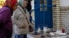 Locals charge their mobile phones with the electricity provided from a generator in front of a shop as there is no electricity in Balakliia, recently liberated by Ukrainian Armed Forces, in Kharkiv region, Sept. 21, 2022. 
