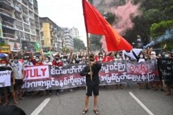Para pengunjuk rasa memegang spanduk bertuliskan, "Berjuang dengan menjaga semangat 7 Juli, hancurkan kediktatoran dari akar dengan segala cara" di Yangon pada 7 Juli 2021. (Foto: AFP)