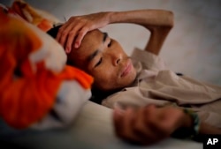Seorang pasien penderita AIDS pada tahap lanjut, terbaring di tempat tidur di Mai Hoa Center untuk para pasien HIV/AIDS di desa An Nhon Tay, Vietnam.
