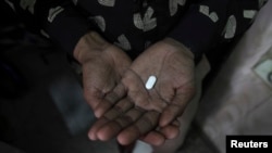 FILE - An HIV patient holds an anti-retroviral drug.