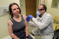 FILE - A pharmacist gives Jennifer Haller, left, the first shot in the first-stage safety study clinical trial of a potential vaccine for COVID-19, the disease caused by the new coronavirus, Monday, March 16, 2020.