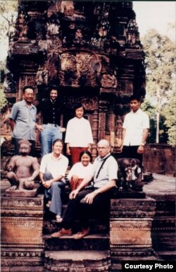 The color photograph of the group includes Richard Dudman (bald), Malcolm Caldwell (flowing hair) and Elizabeth Becker in front of a temple at Angkor Wat. With them are two young aides and Thiounn Prasith, a senior Khmer Rouge official at the Ministry of Foreign Affairs. (Courtesy photo of Elizabeth Becker)