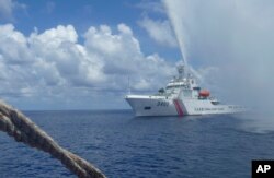 FILE - In this Sept. 23, 2015, file photo, Chinese Coast Guard members approach Filipino fishermen as they confront each other off Scarborough Shoal in the South China Sea, also called the West Philippine Sea.