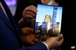 បុរស​ម្នាក់​កាត់​ទូរស័ព្ទ Huawei សេរី Mate X foldable 5G ក្នុង​កម្មវិធី​ Mobile World Congress នៅ​ទីក្រុង Barcelona ប្រទេស អេស្ប៉ាញ ថ្ងៃទី២៦ ខែ​កុម្ភៈ ឆ្នាំ២០១៩។ (AP)