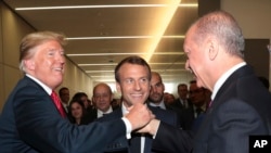 U.S. President Donald Trump, left, shakes hands with Turkey's President Recep Tayyip Erdogan, right, as French President Emmanuel Macron, centre, looks on at the sidelines of a summit of heads of state and government at NATO headquarters in Brussels, Wednesday, July 11, 2018.