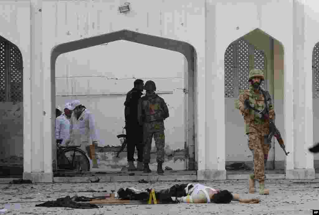 A Pakistani soldier walks past a body of a suicide bomber killed by security forces during an attack on a Shi'ite mosque in Peshawar, Feb. 13, 2015.