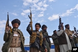Afghan militiamen raise their weapons as they stand guard in the Achin district of Nangarhar province, Afghanistan, Dec. 27, 2015.