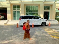 រូប​ឯកសារ៖ ស្ត្រីពីរ​នាក់​ដើរ​កាត់រថយន្តលោកនាយករដ្ឋមន្ត្រី ហ៊ុន សែន នៅមន្ទីរពេទ្យកាល់ម៉ែត រាជធានីភ្នំពេញ កាលពីខែមីនា ឆ្នាំ២០២១។ (អូន ឆេងប៉រ/វីអូអេ)