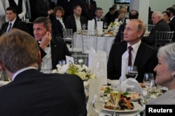 FILE - Russian President Vladimir Putin, right, sits next to retired U.S. Army Lieutenant General Michael Flynn at an exhibition marking the 10th anniversary of the RT (Russia Today) television news channel in Moscow, Russia, Dec.10, 2015.
