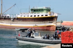 Chinese navy officers dock on the shores of the Gulf of Aden to hand over three suspected pirates involved in the attempted hijacking in April of the OS35, a cargo ship.