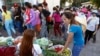 A Cambodian garment worker, foreground right, buys vegetable for her diner near a factory after the day's work, in Phnom Penh, file photo. 