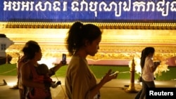 FILE - People walk while using their mobile phones in Phnom Penh, Cambodia, Feb. 18, 2021. The Cambodian government is pushing a controversial internet law the experts say could be used to restrict freedom of speech. Authorities hope to enact a cybercrime law by the end of 2024. 
