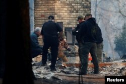 Yuba and Butte County Sheriff deputies retrieve remains of a deceased victim from a home during the Camp Fire in Paradise, California, U.S., Nov. 10, 2018.