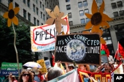 FILE - Climate change activists carry signs as they march in downtown in Philadelphia, July 24, 2016, a day before the start of the Democratic National Convention.