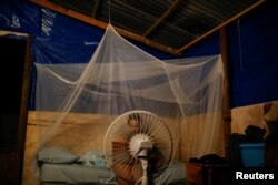 Karla Gerrido works on her computer in front of a fan that works with electricity from a generator, at her house, which was partially destroyed by Hurricane Maria in Canovanas, Puerto Rico, Dec. 11, 2017.