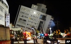 Rescuers are seen entering a building that collapsed onto its side from an early morning 6.4 magnitude earthquake in Hualien County, eastern Taiwan, Wednesday, Feb. 7 2018. Rescue workers are searching for any survivors trapped inside the building.