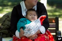 FILE - A child is wrapped up against the cold at a park in Beijing, China.China officially ended its decades-long one-child policy in January.