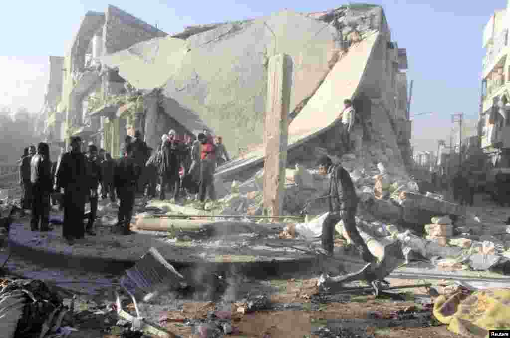 People inspect a site damaged by what activists said was an air raid by forces loyal to Syrian President Bashar Al-Assad in the al-Marja district of Aleppo, Dec. 23, 2013. 