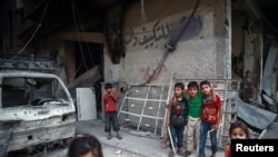 Des enfants sont vus près des décombres de bâtiments endommagés dans la banlieue est de Ghouta, en Syrie, le 17 juillet 2017.