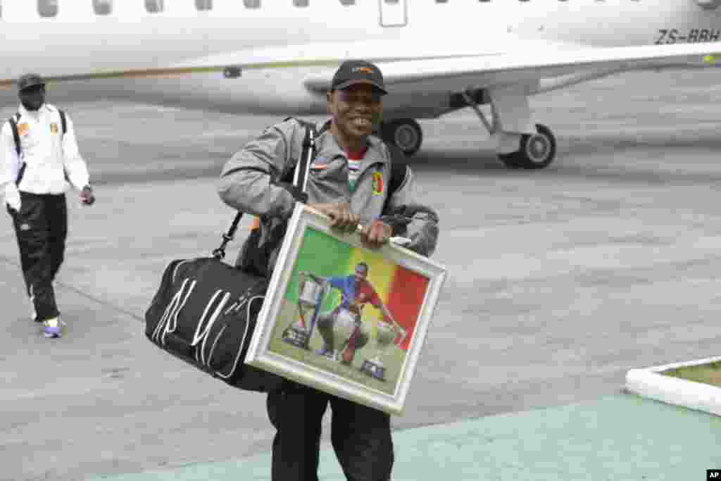 Un membre de la délégation malienne porte un portrait de la star du football malien Seydou Keita à l'arrivée à l'aéroport international de Malabo à Malabo, Guinée équatoriale vendredi 16 janvier 2015.