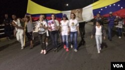 Luz Adriana Chalarca, in white shoes and carrying a figure of the Christ child, leads a prayer vigil on a bridge linking Cúcuta, Colombia, and northwest Venezuela. (C. Mendoza/VOA Spanish Service)