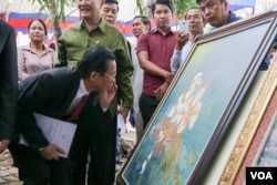 មន្រ្តីក្រសួងវប្បធម៌មួយរូបមើលរូបគំនូររឿងរាមកេរ្ត៍ដែលទទួលបានពានរង្វាន់នៅក្នុងពិធីតាំងពិពណ៌ស្នាដៃសិល្បៈខ្មែរ និងការចែកពានរង្វាន់គំនូររឿងរាមកេរ្តិ៍ នៅថ្ងៃព្រហស្បតិ៍ ទី៣ ខែវិច្ឆិកា ឆ្នាំ២០១៦ រាជធានីភ្នំពេញ។