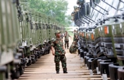 FILE - A Cambodian army soldier looks at Chinese military vehicles displayed before a handover ceremony at a military airbase in Phnom Penh, Cambodia, Wednesday, June 23, 2010.