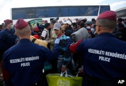 Hungarian police officers stop a group of migrants before a bus that would take the migrants in Roszke, southern Hungary, Sept. 8, 2015.