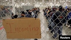 Para imigran ilegal menunggu setelah tiba di tempat penanahan Patroli Perbatasan AS di Nogales, Arizona, 31 Mei 2006.